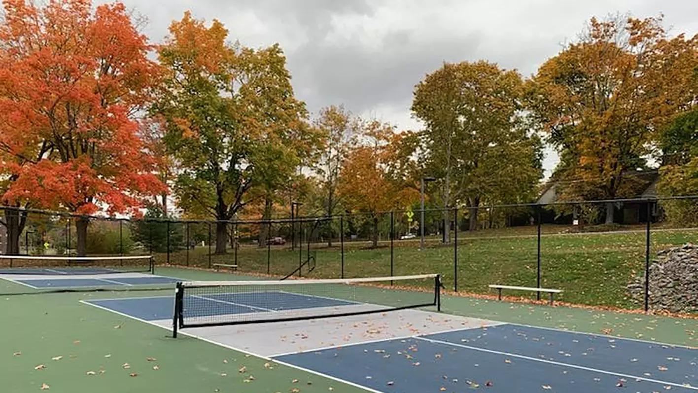 Outdoor pickleball courts surrounded by fall foliage